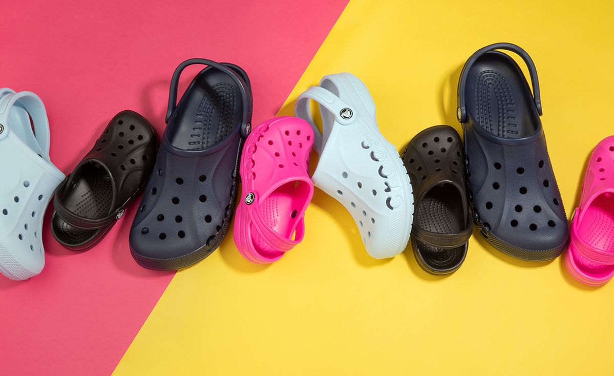 Colorful clogs lined up on pink and yellow